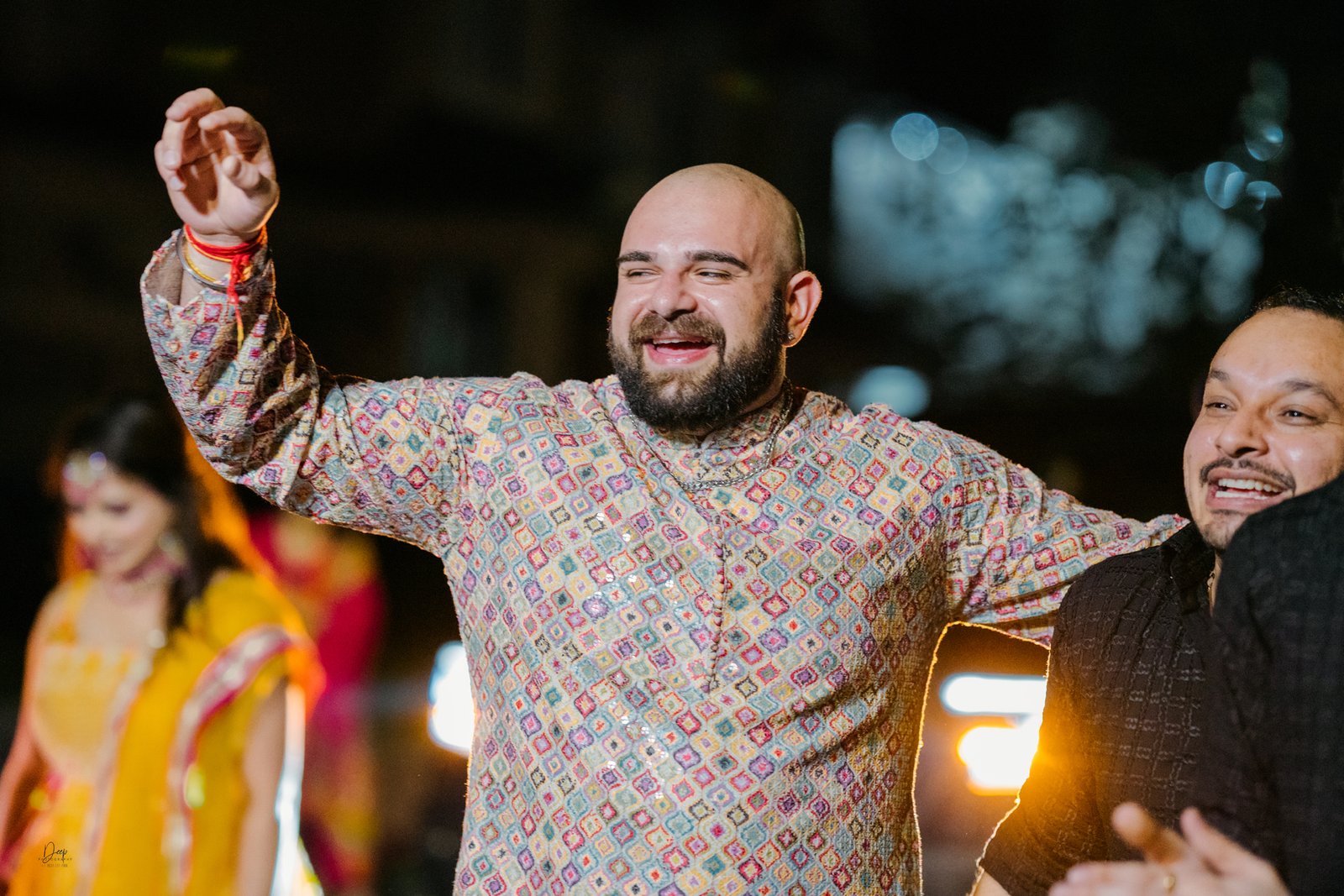 Family celebrating Jaago ceremony with dhol and lights